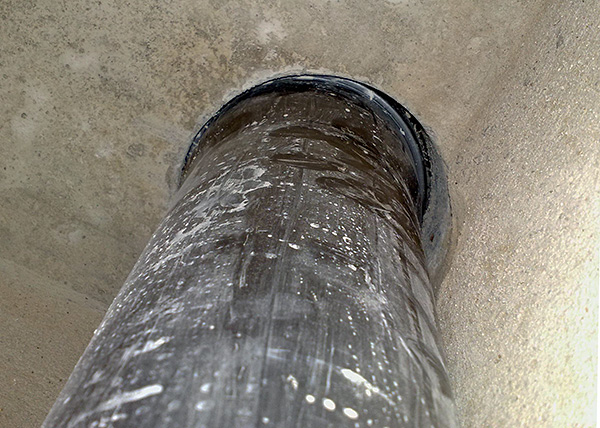Fotografie ukazuje příklad mezery mezi kanalizační trubkou a stěnami otvoru ve stropě toalety.