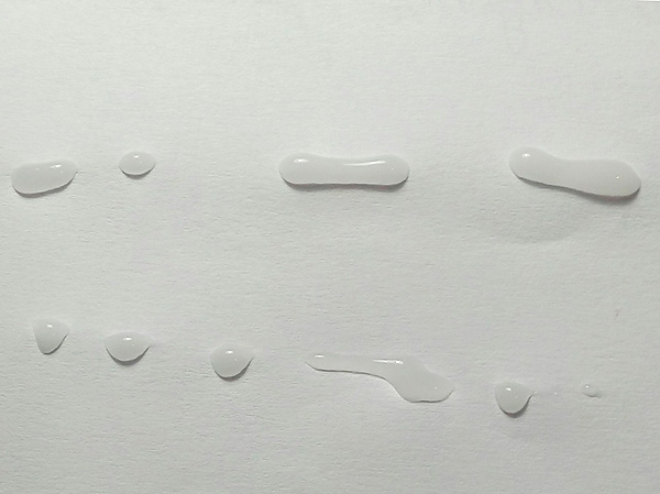 Fotografie ukazuje insekticidní gelové kapičky uložené na papírovém podkladu.
