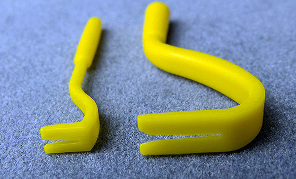 Plast krokformad pincer med en slits i mitten.